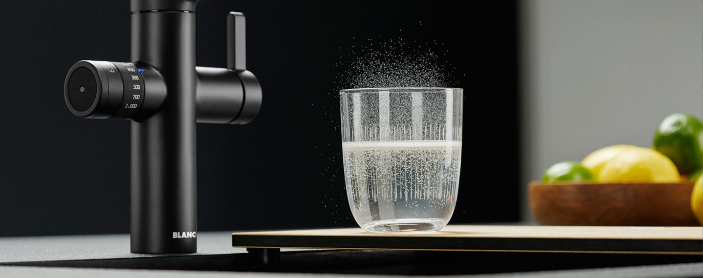 Küche & Concept Foto Headerbild Wasser mit Kohlensäure sprudelt aus dem Glas neben Blanco Wasserhahn