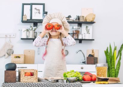 Küche & Concept Foto lachendes Kind in Küche mit Kochmütze und Tomaten vor den Augen